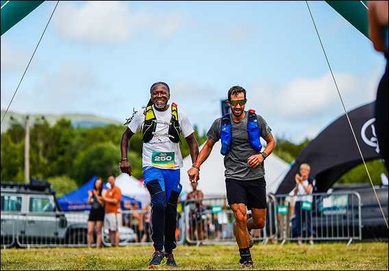 Marathon runners passing through a race gate under clear skies